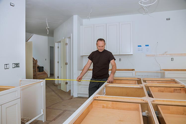 Contractor measuring distance between kitchen cabinets during install
